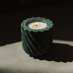 Candle in a green holder on a dark surface