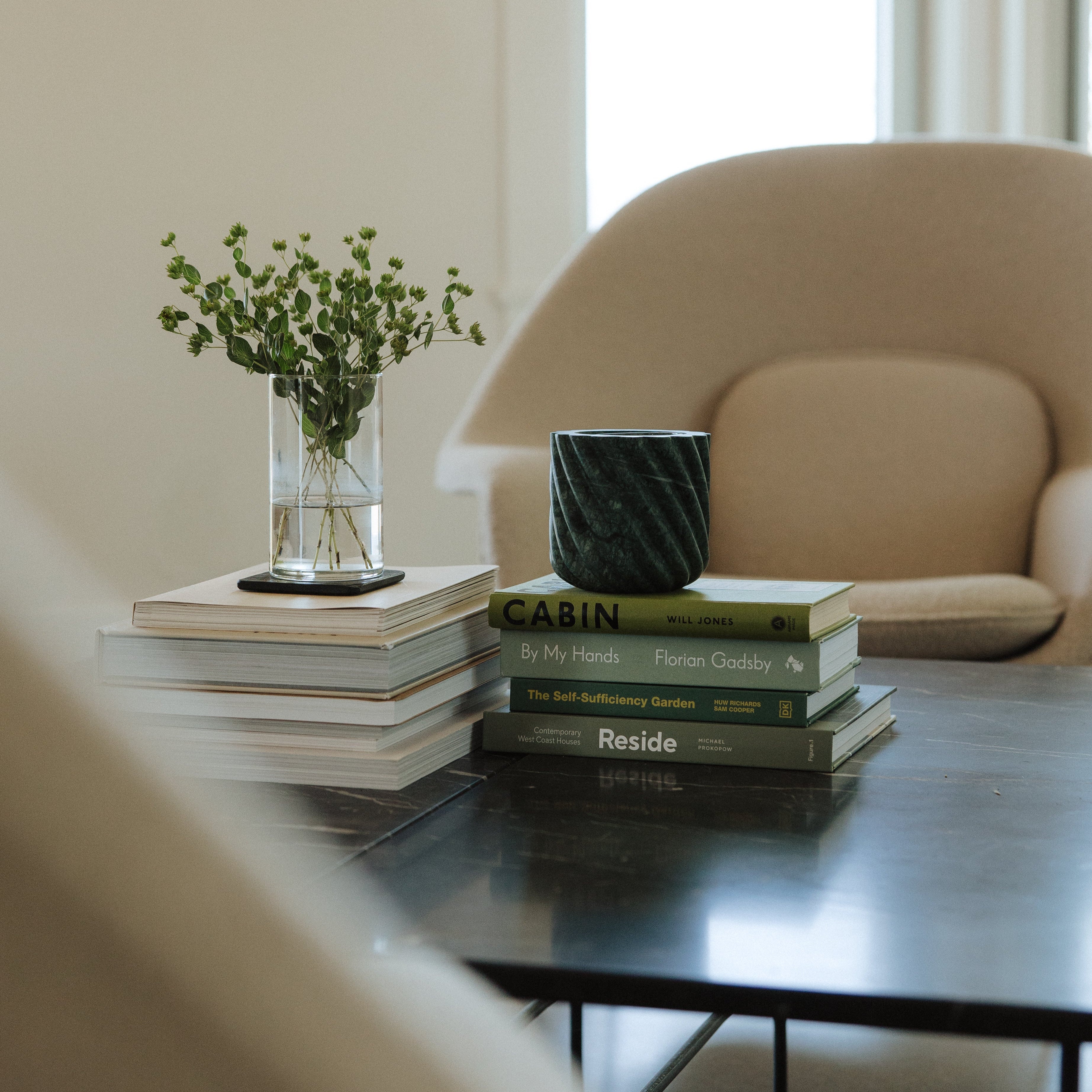 Green textured candle holder on top of a tack of books on a coffee table.