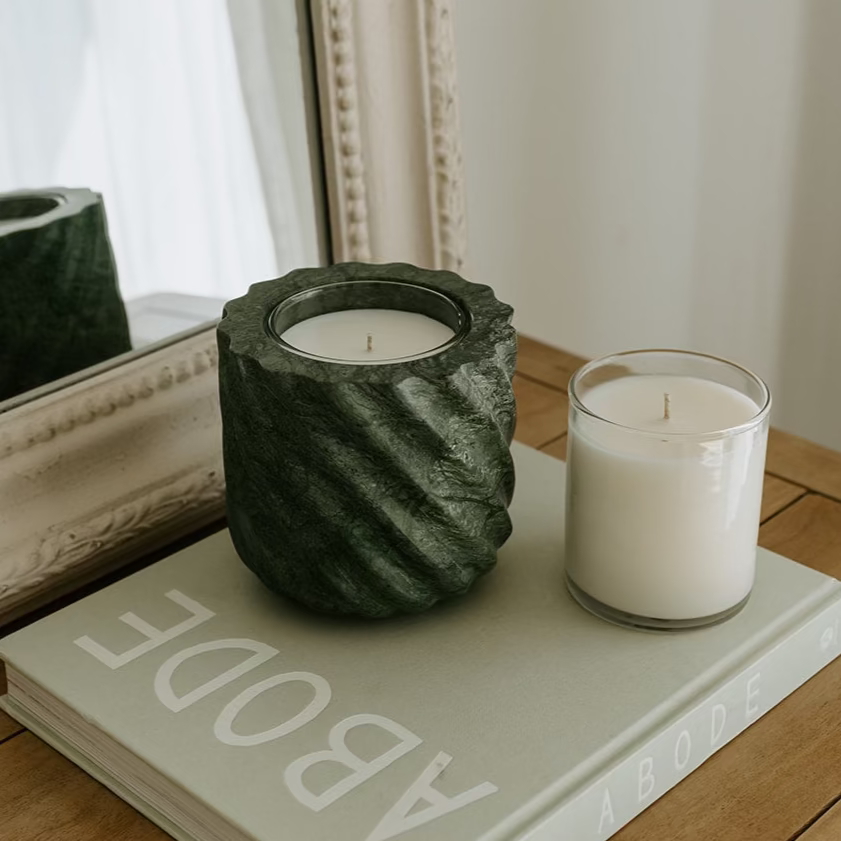 Two candles on a book with a decorative mirror in the background